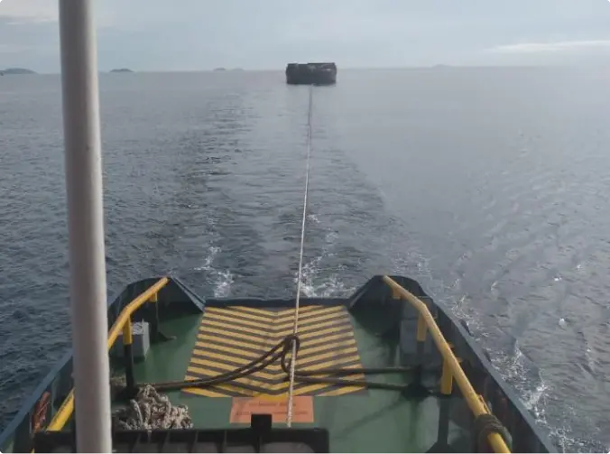 Rear view from a tug boat that is currently towing a barge.